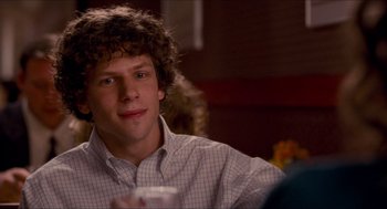 Movie still from “Adventureland” (2009), directed by Greg Mottola – A young man sitting at a table with a drink in front of him; Close Up shot, Over the shoulder angle