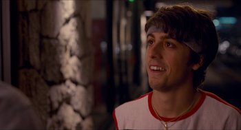 Movie still from “Adventureland” (2009), directed by Greg Mottola – A young man smiling while standing in front of a tree; Close Up shot, Over the shoulder angle
