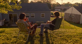 Movie still from “Adventureland” (2009), directed by Greg Mottola – Two people sitting in lawn chairs on a lawn; Wide shot, Low angle