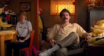 Movie still from “Adventureland” (2009), directed by Greg Mottola – A man sitting on a chair with a remote control; Medium shot, Low angle
