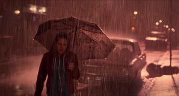 Movie still from “Adventureland” (2009), directed by Greg Mottola – A woman walking down a street holding an open umbrella; Wide shot, High angle