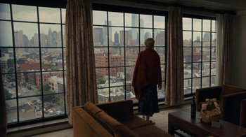 Movie still from “After the Wedding” (2019), directed by Bart Freundlich – A woman standing in front of a window looking out at a city; Wide shot, High angle
