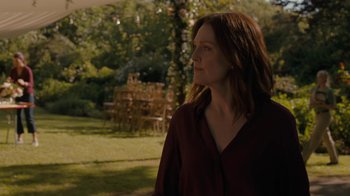 Movie still from “After the Wedding” (2019), directed by Bart Freundlich – A woman standing in the grass near a tree; Medium shot, Over the shoulder angle