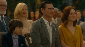Movie still from “After the Wedding” (2019), directed by Bart Freundlich – A man in a gray suit sitting next to a woman in a white shirt; Medium shot, Over the shoulder angle