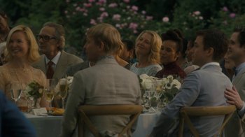 Movie still from “After the Wedding” (2019), directed by Bart Freundlich – A group of people sitting at a table with glasses; Medium shot, Over the shoulder angle