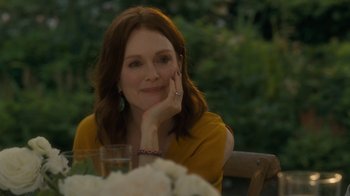 Movie still from “After the Wedding” (2019), directed by Bart Freundlich – Julianne moore sitting at a table in front of flowers; Close Up shot, Over the shoulder angle