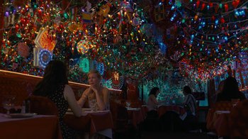 Movie still from “After the Wedding” (2019), directed by Bart Freundlich – People sitting at a table in front of christmas lights; Extreme Wide shot, Over the shoulder angle