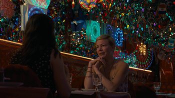Movie still from “After the Wedding” (2019), directed by Bart Freundlich – A woman sitting at a table with a glass of wine in front of her; Medium shot, Over the shoulder angle