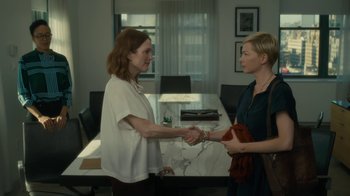 Movie still from “After the Wedding” (2019), directed by Bart Freundlich – Two women shaking hands in a conference room; Medium shot, Over the shoulder angle