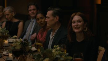 Movie still from “After the Wedding” (2019), directed by Bart Freundlich – A group of people sitting at a dinner table; Medium shot, Over the shoulder angle