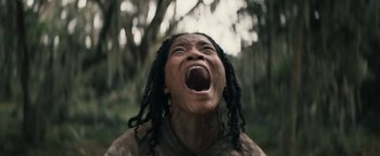 Movie still from “Alice” (2022), directed by Krystin Ver Linden – A woman with dreadlocks is screaming with her mouth wide open; Extreme Close Up shot, Low angle