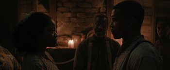 Movie still from “Alice” (2022), directed by Krystin Ver Linden – A group of people standing in front of a brick wall; Close Up shot, Over the shoulder angle