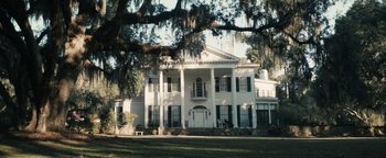Movie still from “Alice” (2022), directed by Krystin Ver Linden – A large white house sitting in the middle of a field; Extreme Wide shot, Low angle
