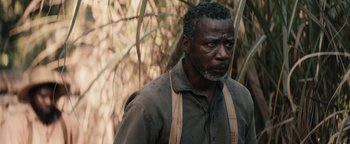 Movie still from “Alice” (2022), directed by Krystin Ver Linden – An older man with a beard wearing a brown shirt and suspenders looking to his left; Close Up shot, Over the shoulder angle