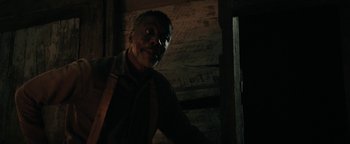 Movie still from “Alice” (2022), directed by Krystin Ver Linden – A man in a dark room looking at the camera; Close Up shot, Over the shoulder angle