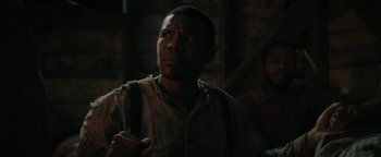 Movie still from “Alice” (2022), directed by Krystin Ver Linden – A black man is holding a cell phone in a dark room; Close Up shot, Over the shoulder angle