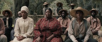 Movie still from “Alice” (2022), directed by Krystin Ver Linden – A group of men and women sitting in front of a fence; Medium shot, Over the shoulder angle
