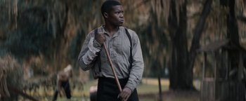Movie still from “Alice” (2022), directed by Krystin Ver Linden – A man holding a wooden stick in a park; Medium shot, Over the shoulder angle