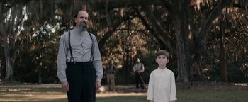 Movie still from “Alice” (2022), directed by Krystin Ver Linden – A man and a boy standing next to each other in a field; Medium shot, Over the shoulder angle