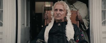 Movie still from “Alice” (2022), directed by Krystin Ver Linden – An old woman wearing a white head scarf and holding a cane; Close Up shot, Over the shoulder angle