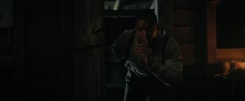 Movie still from “Alice” (2022), directed by Krystin Ver Linden – A man standing next to a wooden door; Medium shot, Over the shoulder angle