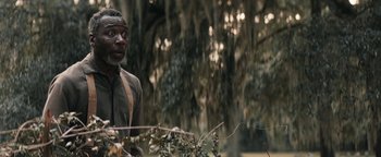 Movie still from “Alice” (2022), directed by Krystin Ver Linden – A man standing next to a tree in the woods; Close Up shot, Over the shoulder angle