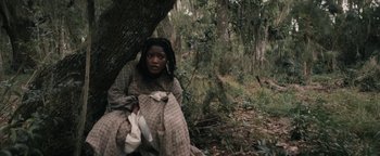 Movie still from “Alice” (2022), directed by Krystin Ver Linden – A woman sitting in a tree in the woods; Medium shot, High angle