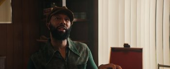 Movie still from “Alice” (2022), directed by Krystin Ver Linden – A man with a beard wearing a hat and a plaid shirt; Close Up shot, Over the shoulder angle