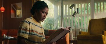Movie still from “Alice” (2022), directed by Krystin Ver Linden – A woman is reading a book in a living room; Medium shot, Low angle