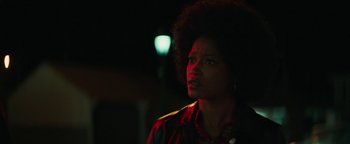 Movie still from “Alice” (2022), directed by Krystin Ver Linden – A woman in a red shirt is standing in the dark; Close Up shot, Over the shoulder angle