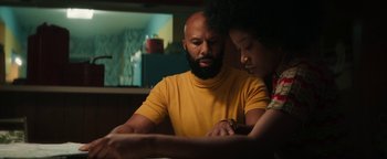 Movie still from “Alice” (2022), directed by Krystin Ver Linden – A man and a woman are looking at something on a table; Medium shot, Over the shoulder angle