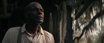 Movie still from “Alice” (2022), directed by Krystin Ver Linden – A man with a beard and a white shirt is looking at the camera; Close Up shot, Low angle