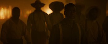 Movie still from “Alice” (2022), directed by Krystin Ver Linden – A group of men standing next to each other in the dark; Medium shot, Over the shoulder angle