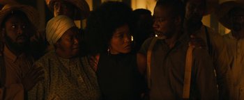 Movie still from “Alice” (2022), directed by Krystin Ver Linden – A group of people standing next to each other in the dark; Close Up shot, Over the shoulder angle