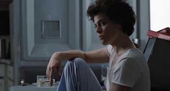 Movie still from “Aliens” (1986), directed by James Cameron – A woman sitting on the floor in a room; Medium shot, Low angle
