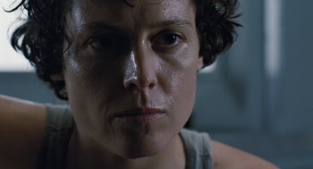 Movie still from “Aliens” (1986), directed by James Cameron – A woman's face with a dark background; Close Up shot, Low angle