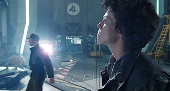 Movie still from “Aliens” (1986), directed by James Cameron – A man standing in front of a building looking out the window; Medium shot, Low angle