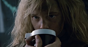 Movie still from “Aliens” (1986), directed by James Cameron – A person with long blonde hair is drinking a cup of coffee; Extreme Close Up shot, Low angle