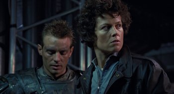 Movie still from “Aliens” (1986), directed by James Cameron – A man standing next to a woman wearing a black jacket; Close Up shot, Low angle
