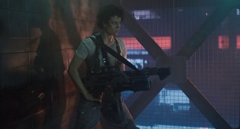Movie still from “Aliens” (1986), directed by James Cameron – A man holding a video camera while standing next to a wall; Medium shot, Low angle