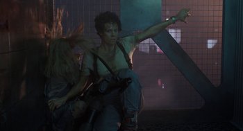 Movie still from “Aliens” (1986), directed by James Cameron – A woman riding on the back of a motorcycle in the dark; Medium shot, Low angle