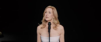 A woman in a strapless white top is singing