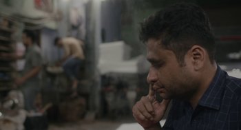 Movie still from “All That Breathes” (2022), directed by Shaunak Sen – A person with his hand to his face; Close Up shot, Low angle