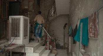 Movie still from “All That Breathes” (2022), directed by Shaunak Sen – A man walking down a set of stairs; Wide shot, High angle
