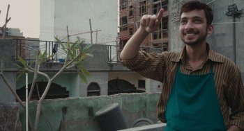 Movie still from “All That Breathes” (2022), directed by Shaunak Sen – A man in an overalls pointing to the sky; Medium shot, Low angle