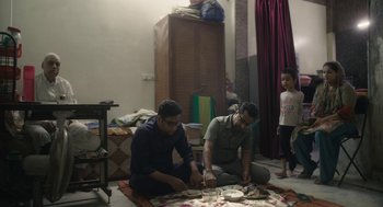 Movie still from “All That Breathes” (2022), directed by Shaunak Sen – A group of people sitting on the floor in a room; Medium shot, Low angle