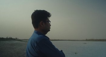 Movie still from “All That Breathes” (2022), directed by Shaunak Sen – A man standing on the beach looking out at the water; Close Up shot, Low angle