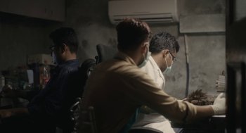 Movie still from “All That Breathes” (2022), directed by Shaunak Sen – A group of people sitting in a room; Wide shot, Low angle