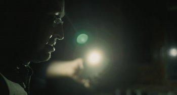 Movie still from “All That Breathes” (2022), directed by Shaunak Sen – A man looking at a flashlight in the dark; Extreme Close Up shot, Low angle