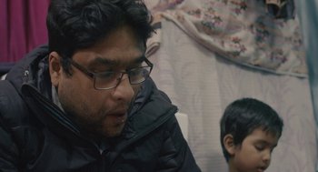 Movie still from “All That Breathes” (2022), directed by Shaunak Sen – A man wearing glasses and a black jacket; Close Up shot, High angle